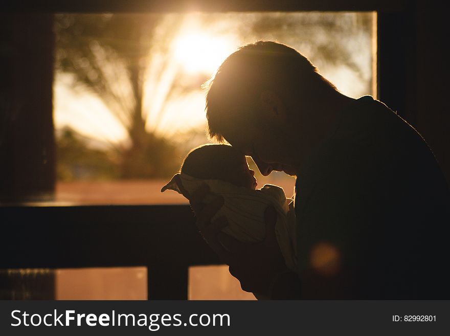 Man Carrying Baby Drawing Their Foreheads