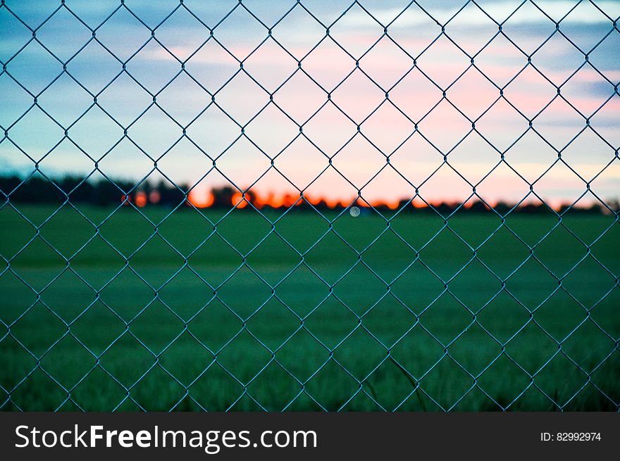 Sunset Over Field Through Fence