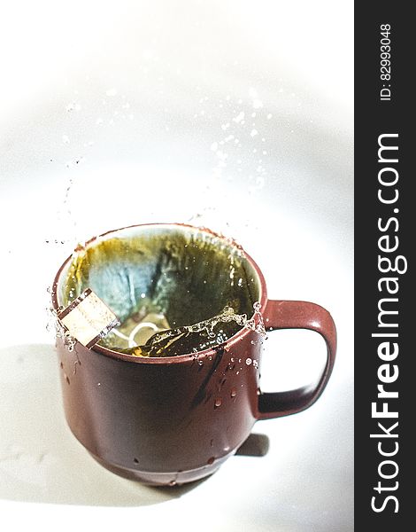 Close up of tea bag splashing in water in brown mug. Close up of tea bag splashing in water in brown mug.