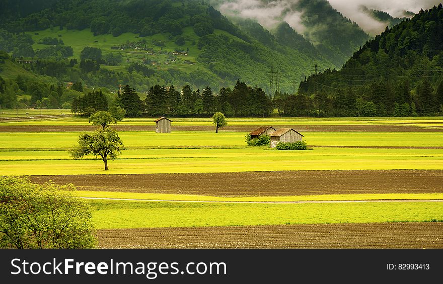 Brown House in the Middle of Green Field Grass Near Mountains