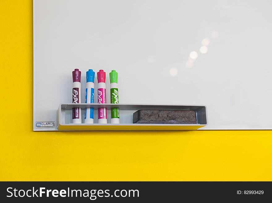 Colorful markers and eraser at whiteboard on yellow wall. Colorful markers and eraser at whiteboard on yellow wall.