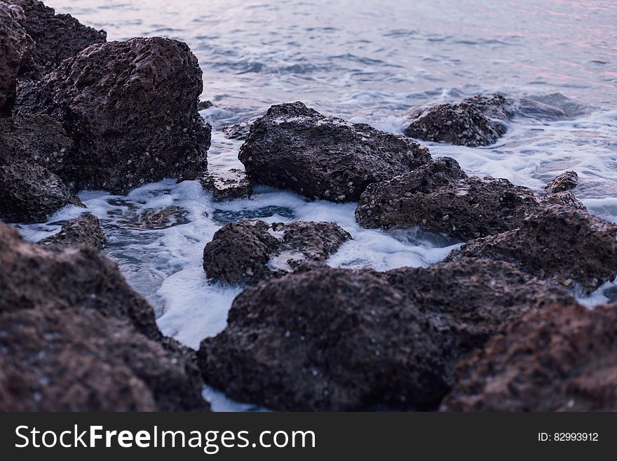Black and Brown Rocks on Sea during Daylight