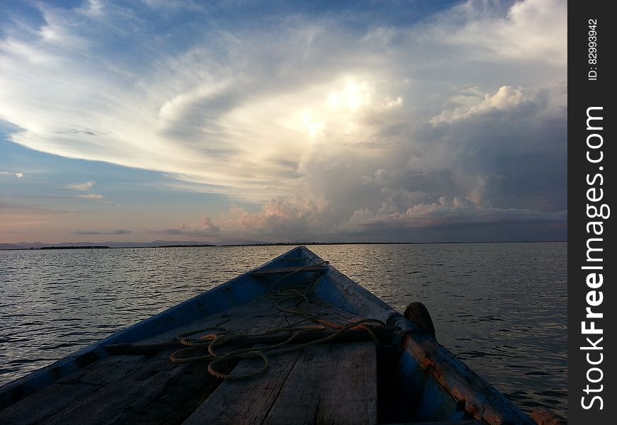 Blue Rowboat On Water Under White Clouds During Daytime