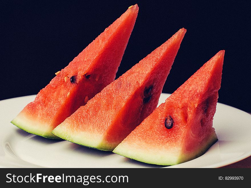 Slices of fresh watermelon on white china plate with black background. Slices of fresh watermelon on white china plate with black background.