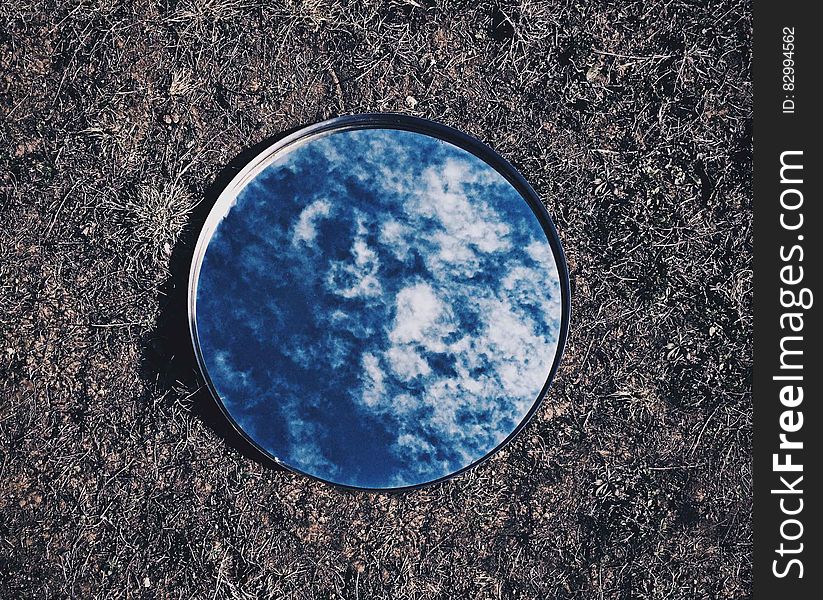 Round mirror lying on grass reflecting blue sky and clouds. Round mirror lying on grass reflecting blue sky and clouds.