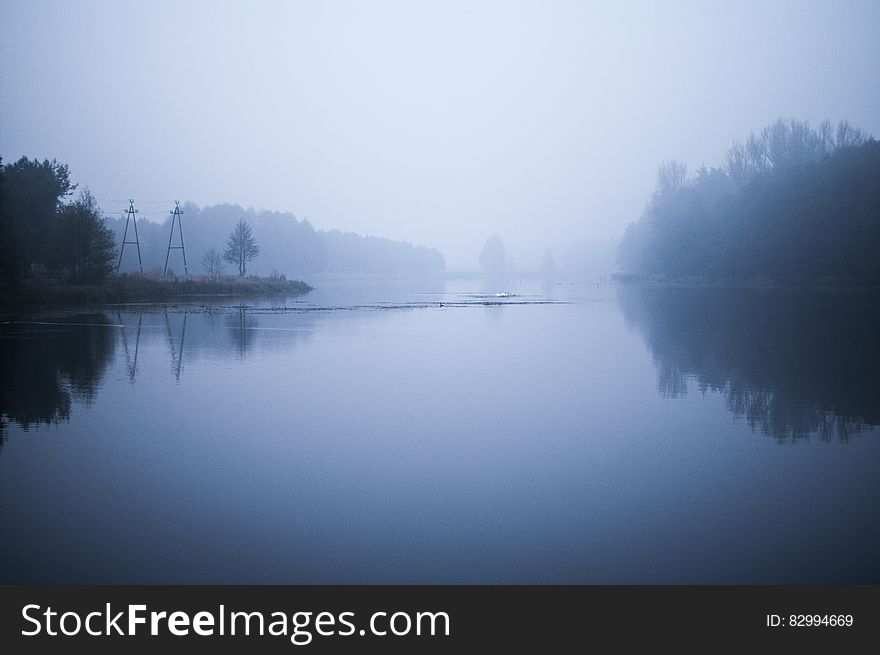 Fog over tree lined river banks in early morning. Fog over tree lined river banks in early morning.