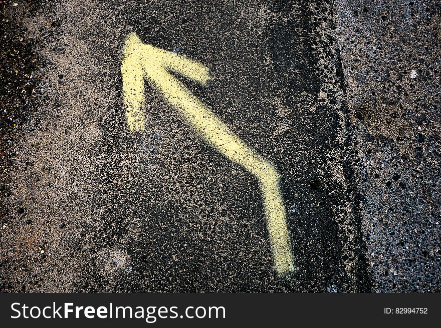 Yellow Left Arrow Sign On Black And Grey Surface