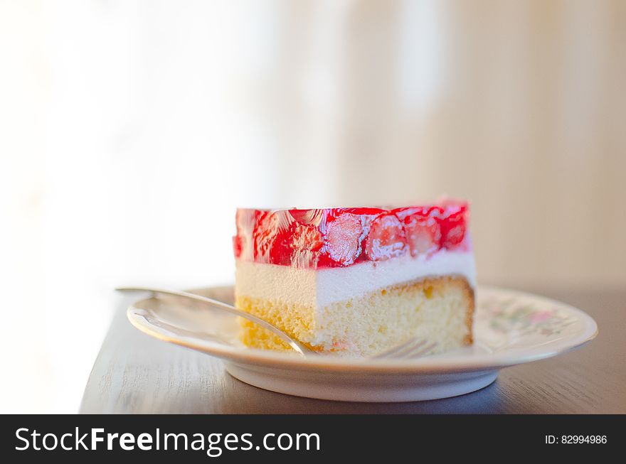 Slice of strawberry dessert cake on small plate with spoon.