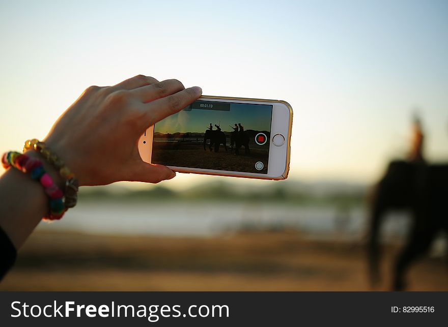 Hand of woman taking video of person riding elephant with smartphone. Hand of woman taking video of person riding elephant with smartphone