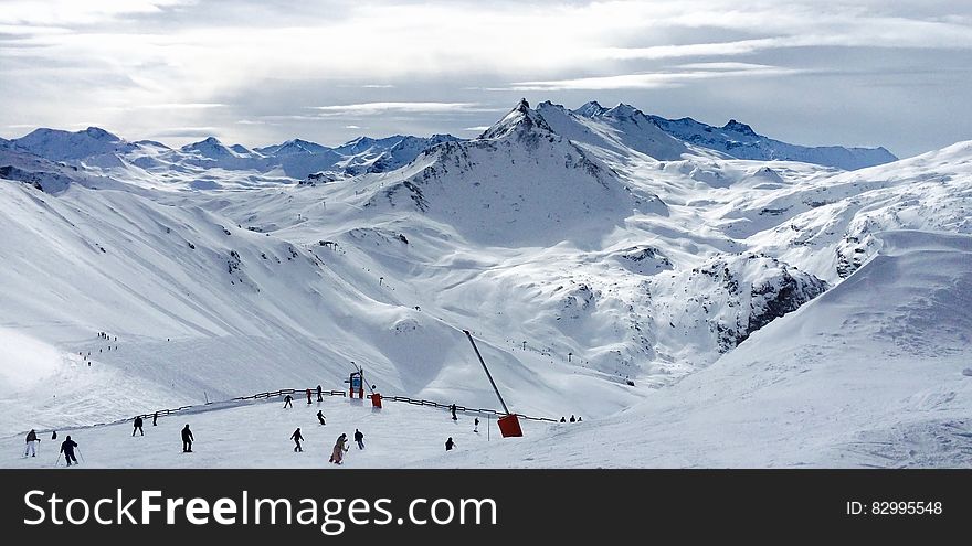 People Lurking Around on Snow Field Near Mountains
