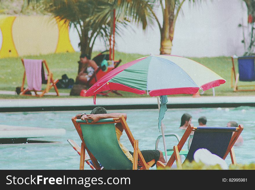 Person Lying on Bench Near Swimming Pool