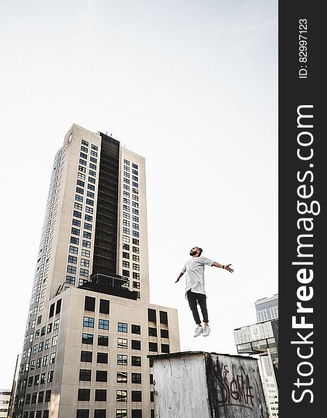 Man Wearing White Long Sleeve Shirt Beside White And Black High Rise Building