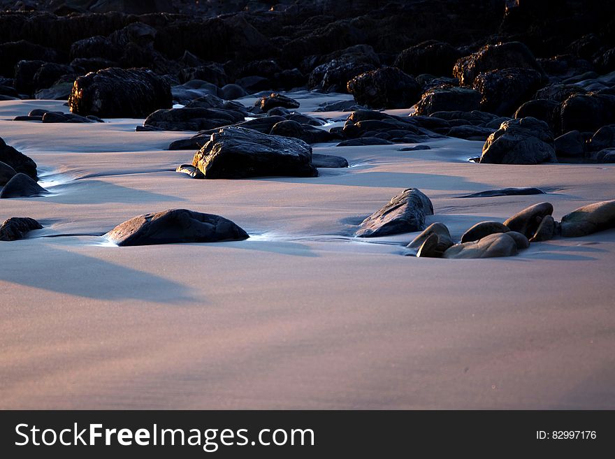 Black Rocks on Sand during Daytime