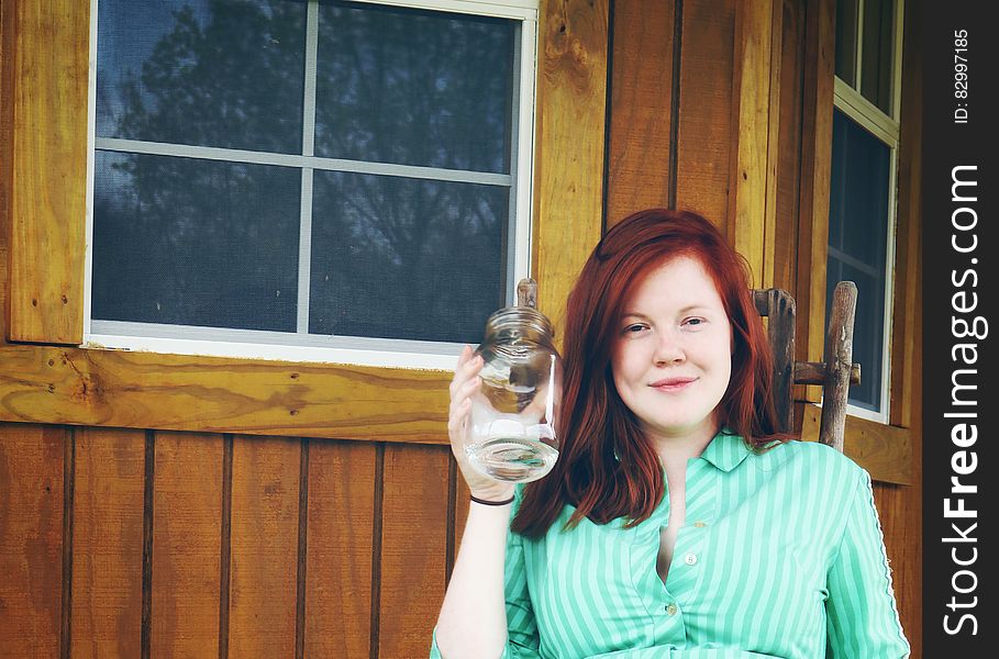 Woman in Green Button Up Collared Shirt Holding Clear Glass