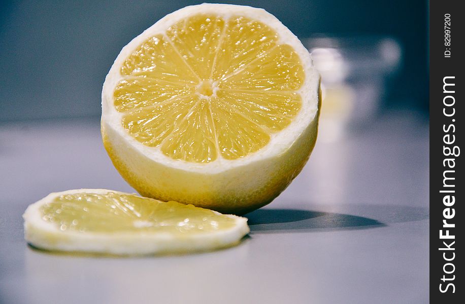 Slice of fresh lemon next to fruit on counter.