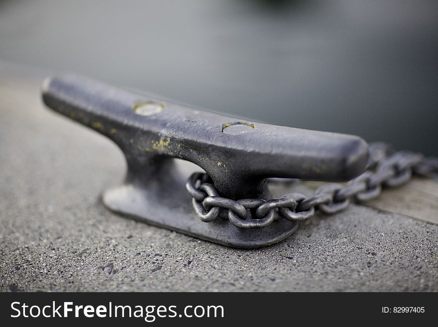 Close up of metal boat tie with chain on waterfront.