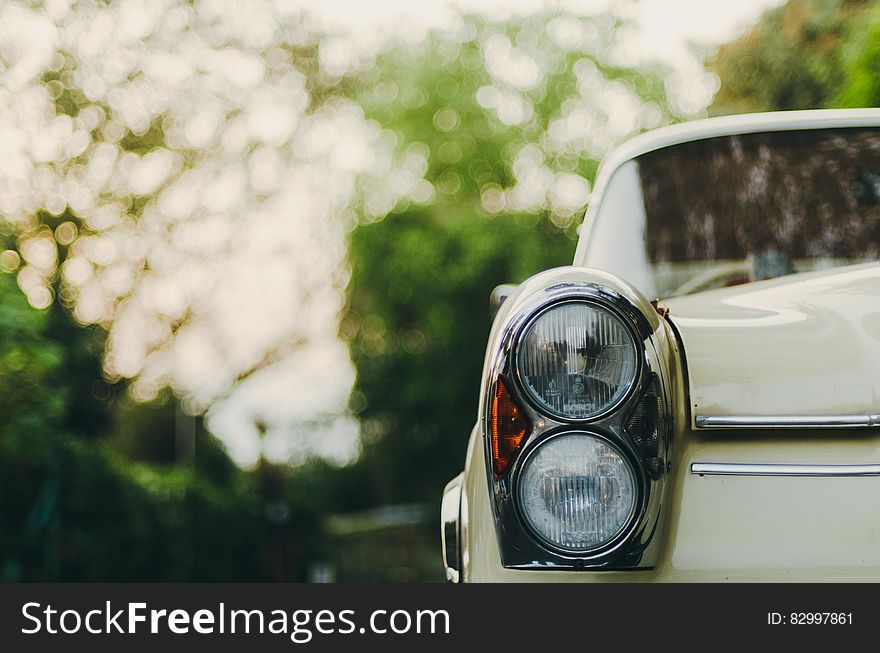 Headlight and fender on vintage Mercedes auto on sunny street.