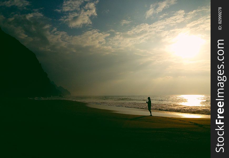 Silhouette of person standing on sandy beach at sunset. Silhouette of person standing on sandy beach at sunset.