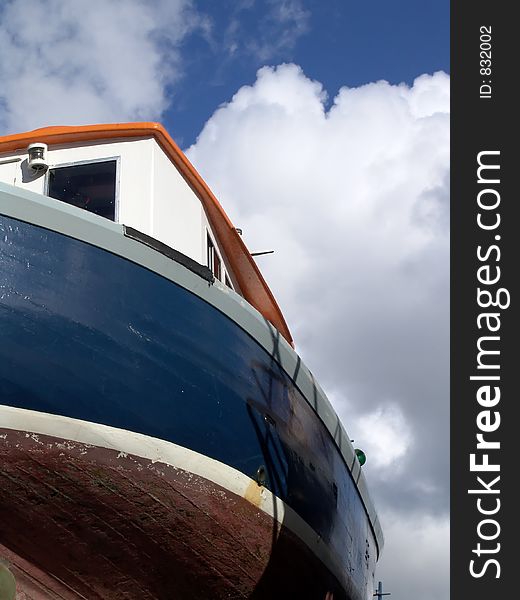 Old boat shot from below with blue sky and white cloud background. Old boat shot from below with blue sky and white cloud background.
