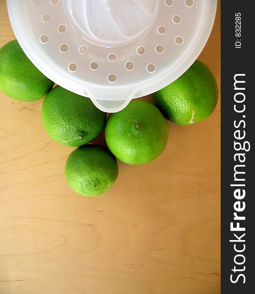 A fruit squeezer with fresh green limes. Focused at the fruit squeezer. A fruit squeezer with fresh green limes. Focused at the fruit squeezer.