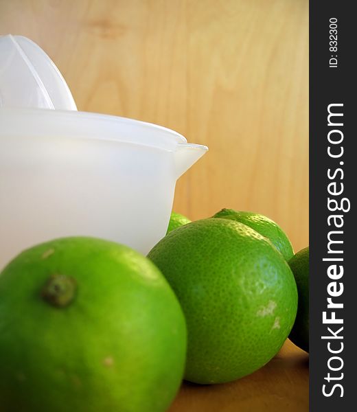 A fruit squeezer with fresh green limes. Focused at the fruit squeezer. A fruit squeezer with fresh green limes. Focused at the fruit squeezer.