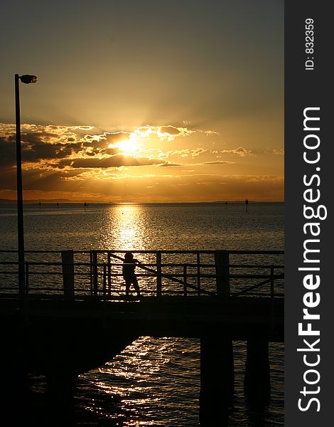 A small child playing in the last rays of light of the day on a jetty. Beautiful ocean view. Location: Stradbroke Island, Queensland, Australia. A small child playing in the last rays of light of the day on a jetty. Beautiful ocean view. Location: Stradbroke Island, Queensland, Australia.