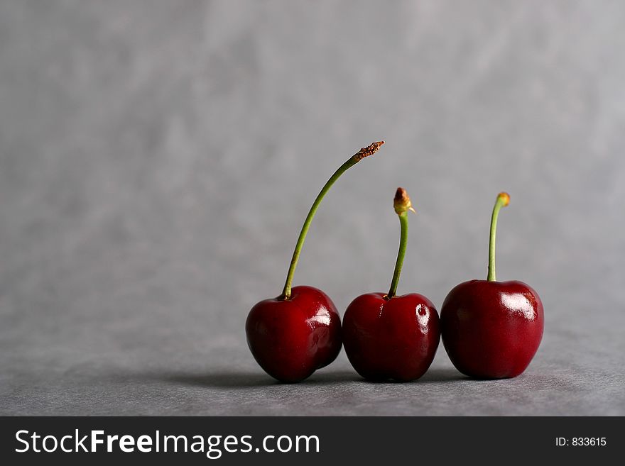 Three cherries on grey background. Three cherries on grey background