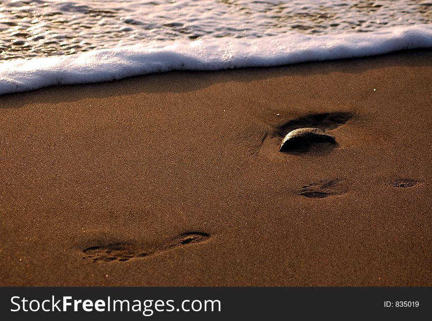 Footprints in the sand being washed away.