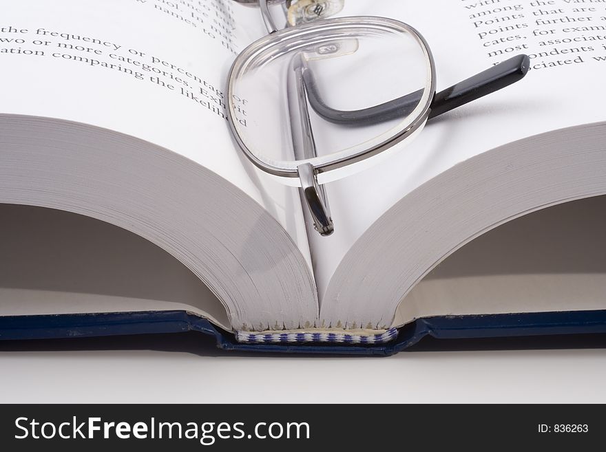 Close-up of an open book with eye-glasses