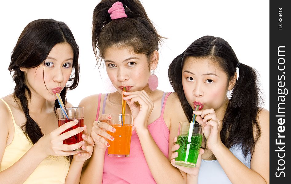 Thre pretty asian women drinking colored drinks from glasses with straws. Thre pretty asian women drinking colored drinks from glasses with straws