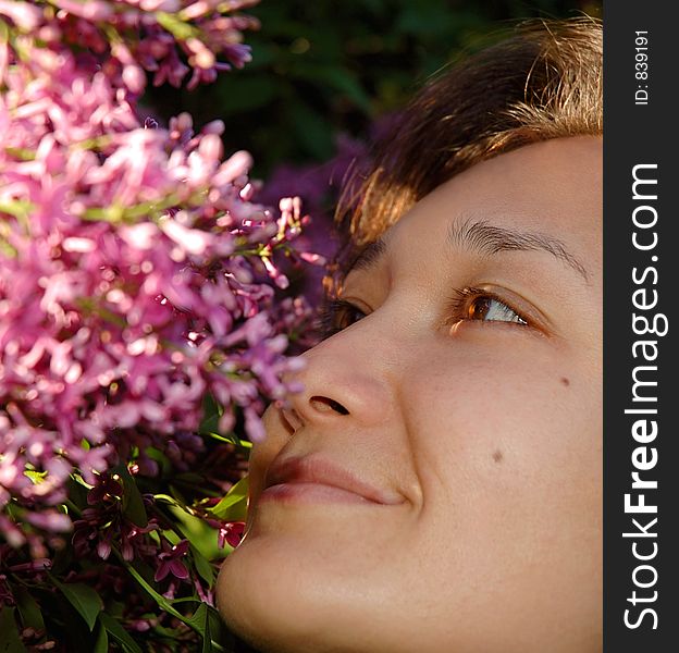 Happy girl smelling liliac flowers