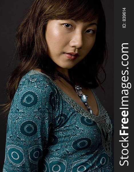 A cute young asian model in green dress on black background