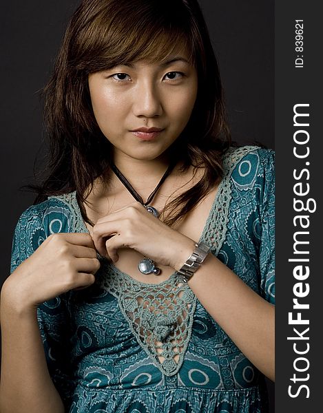 A beautiful young asian woman in patterned dress on black background. A beautiful young asian woman in patterned dress on black background