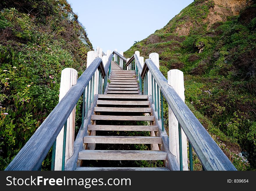 Outdoor wooden stairs at sunset leading to the beach.