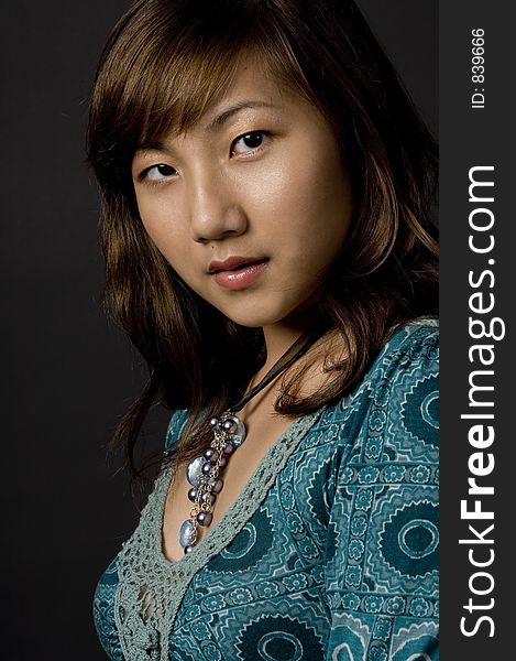 A beautiful young asian woman in patterned dress on black background. A beautiful young asian woman in patterned dress on black background