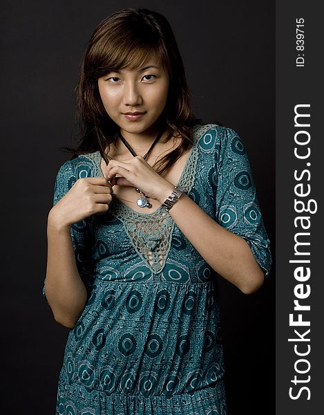 A pretty young asian woman in blue green dress on black background. A pretty young asian woman in blue green dress on black background