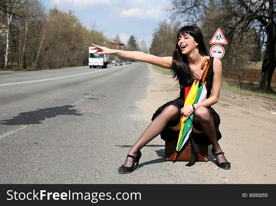 Girl in the road sit atop vintage suitcase with umbrella. Girl in the road sit atop vintage suitcase with umbrella