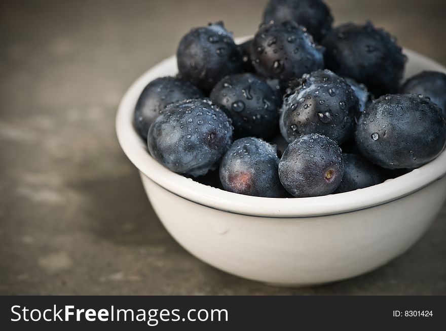 Ripe blueberries moistened with droplets of water in a small bowl. Ripe blueberries moistened with droplets of water in a small bowl.