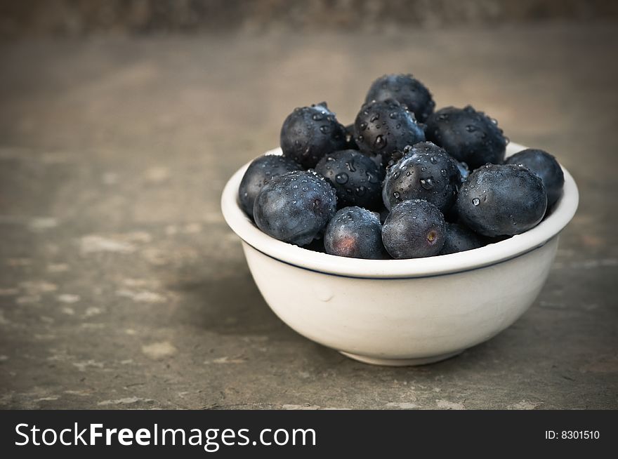 Fresh blueberries sprinkled with water in a small bowl.