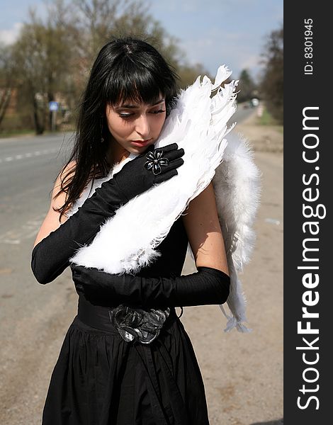 Black angel with white broken wing outdoors. Black angel with white broken wing outdoors