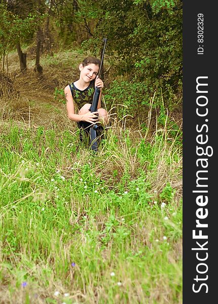 Beauty teen girl with gun in forest