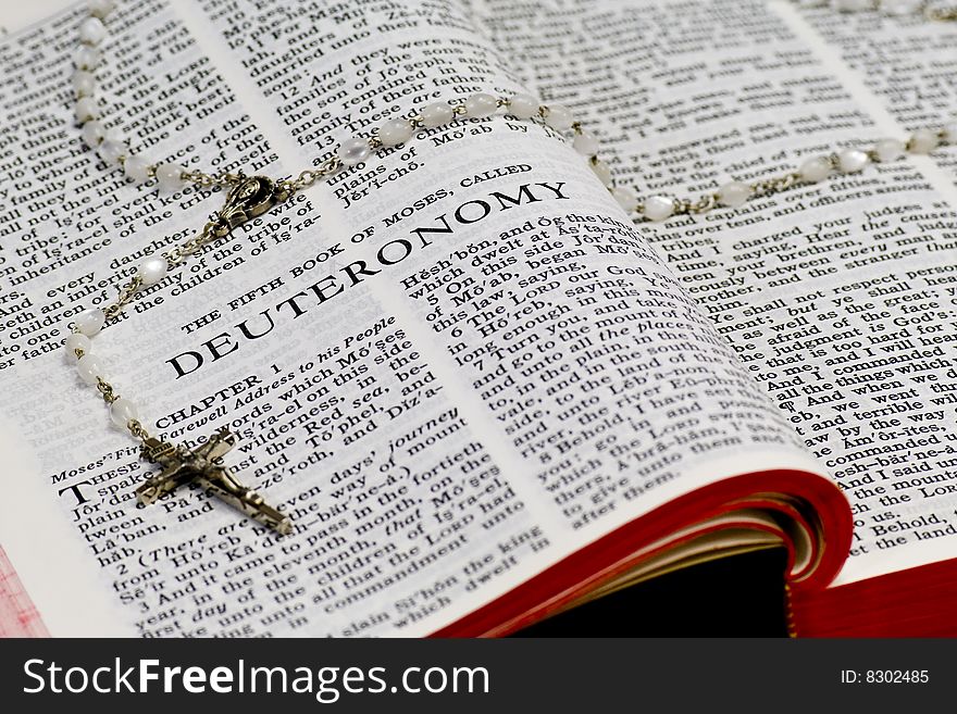 Close up of Deuteronomy bible page with rosary. Close up of Deuteronomy bible page with rosary