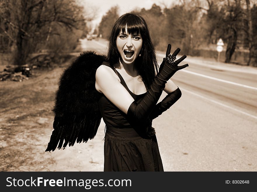 Screaming black angel outdoors in sepia toned