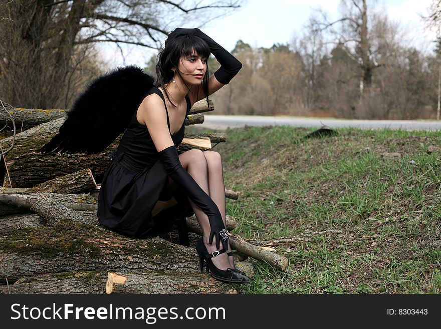 Sitting lovely black angel outdoors