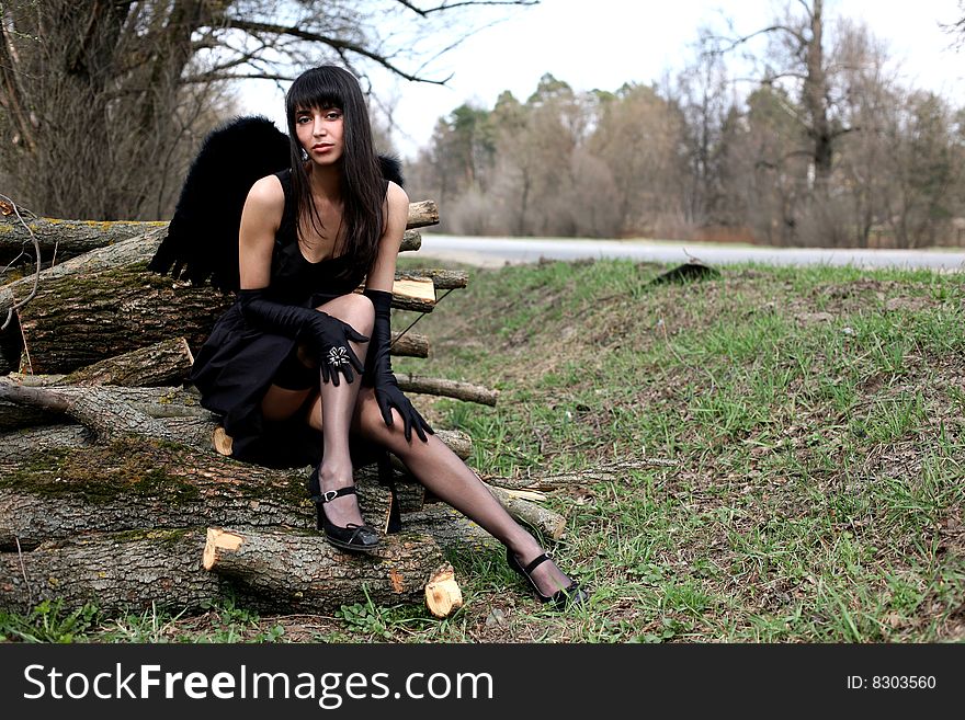 Lovely black angel outdoors in black dress
