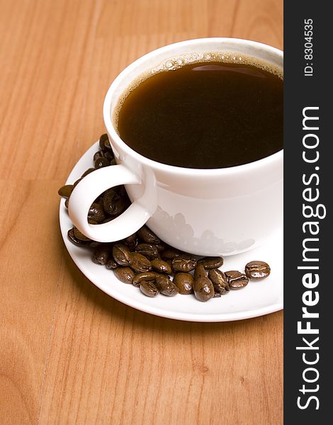 Cup of coffee and beans closeup on wooden table