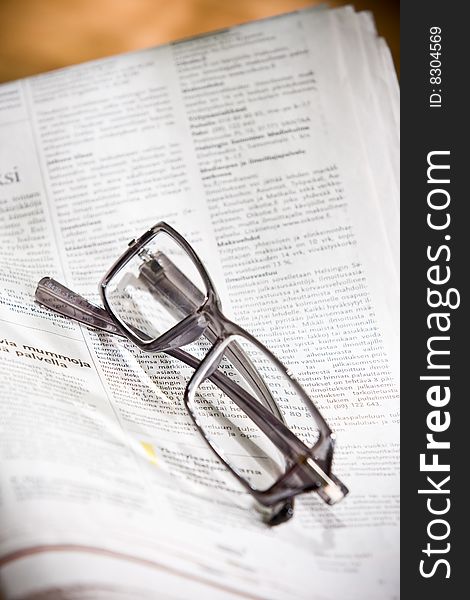 Eyeglasses and newspaper on the table.