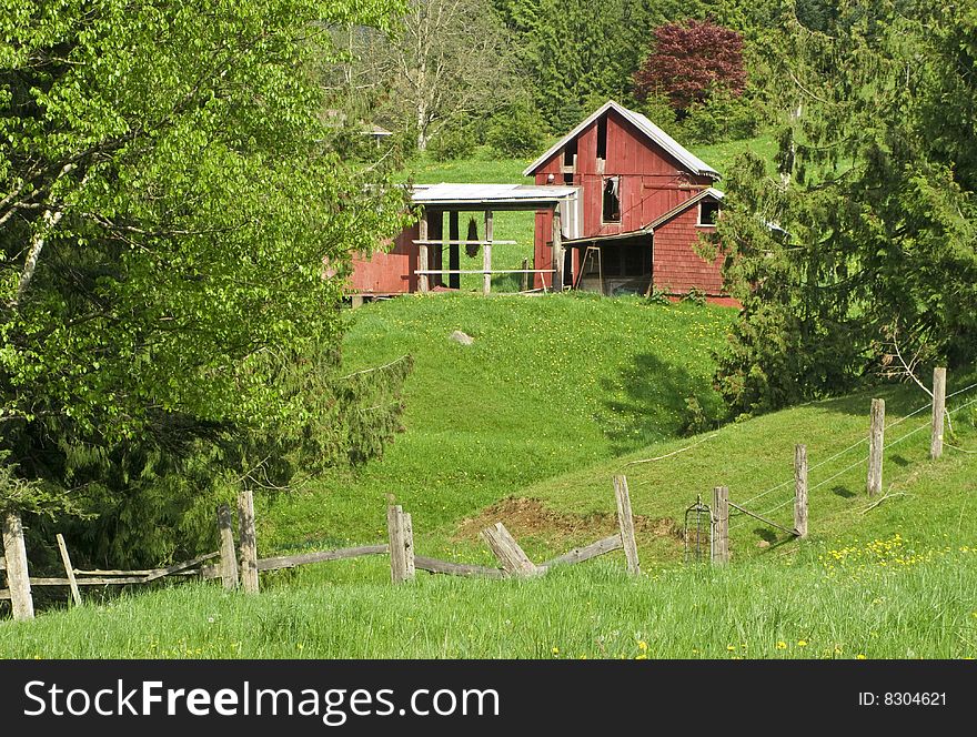 A hillside farm scene with a barn fence and field