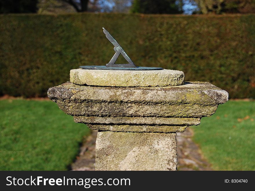 Old sundial in garden on a stone plinth