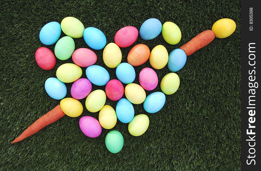 Colorful easter egg heart with carrot arrow on the green grass. Colorful easter egg heart with carrot arrow on the green grass